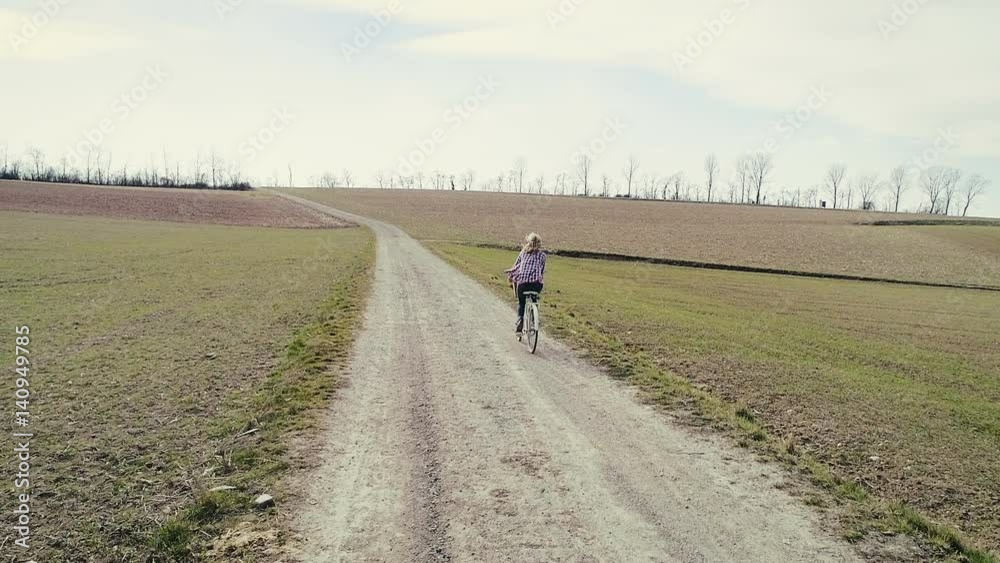 junge, hübsche, blonde frau fährt auf vintage fahrrad auf einem feldweg junge, hübsche, blonde frau fährt auf vintage fahrrad auf einem feldweg