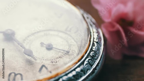 Close-up of pocket watch Next to a gently pink violet flower and passage of time photo