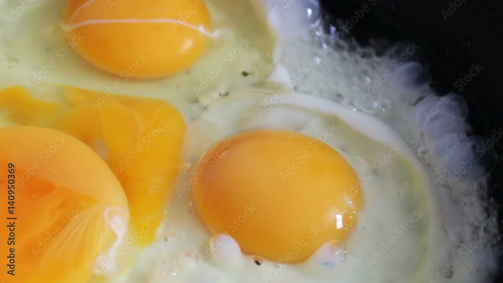 Preparing scrambled eggs close up on hot frying pan