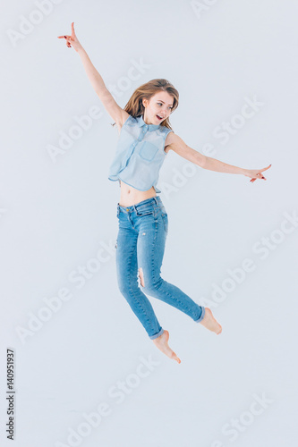 Happy, young, beautiful girl on a white background in a jump