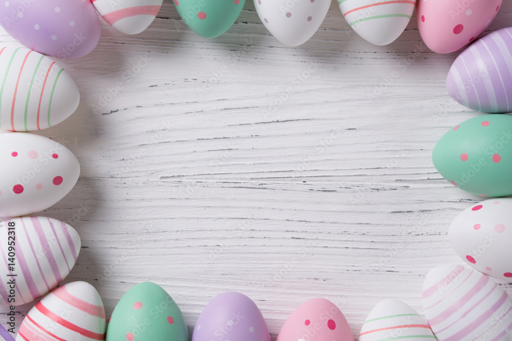 Easter background with frame made of colored easter eggs, top view with copy space
