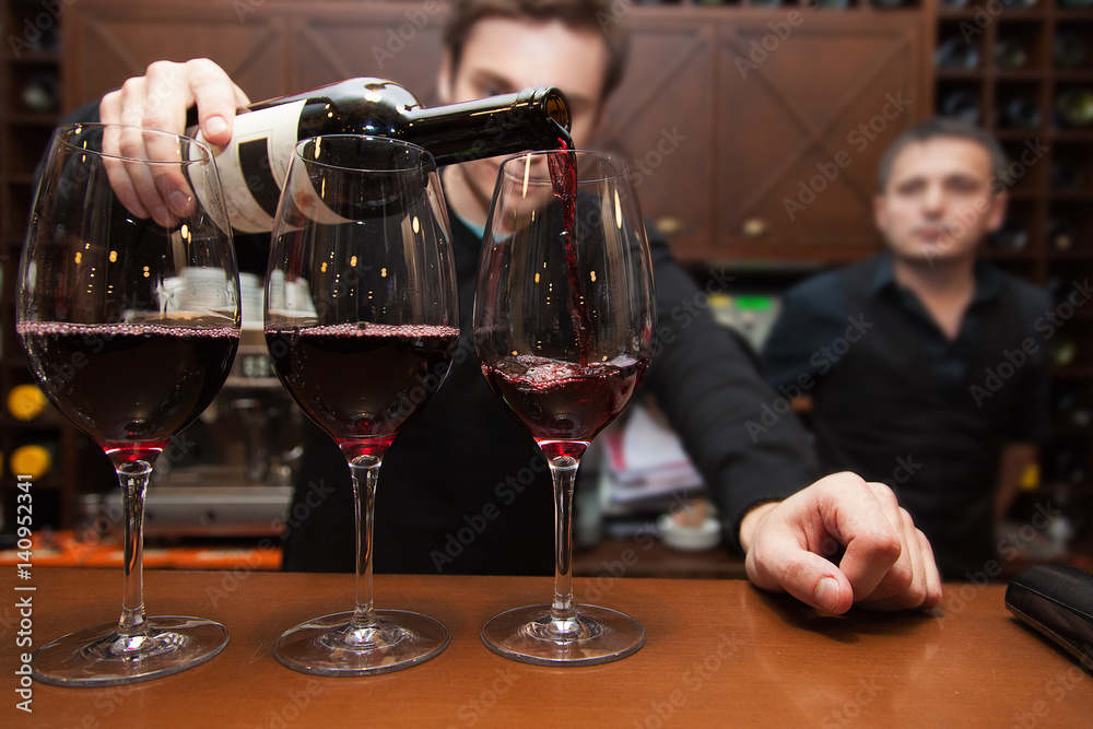 sommelier pouring red wine into a glass sommelier pouring red wine into a glass