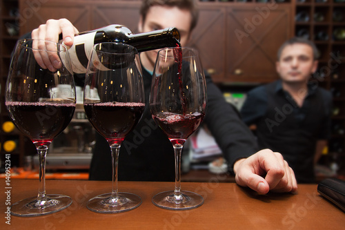 sommelier pouring red wine into a glass