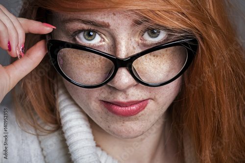 Portrait of a redhead freckled girl in glasses