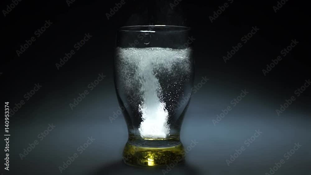 Effervescent tablet dissolves in a glass with water on a black background slow motion Effervescent tablet dissolves in a glass with water on a black background slow motion