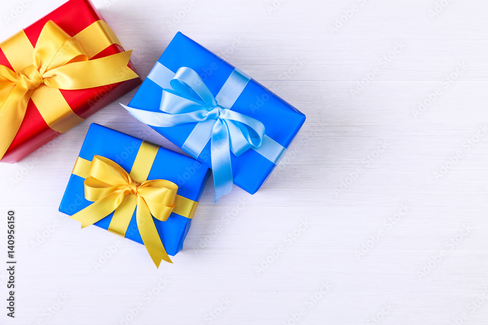 Gift boxes with bow. Presents wrapped with paper and ribbons. Christmas or birthday packages. Celebration design. On white wooden table. Gift boxes with bow. Presents wrapped with paper and ribbons. Christmas or birthday packages. Celebration design. On white wooden table.
