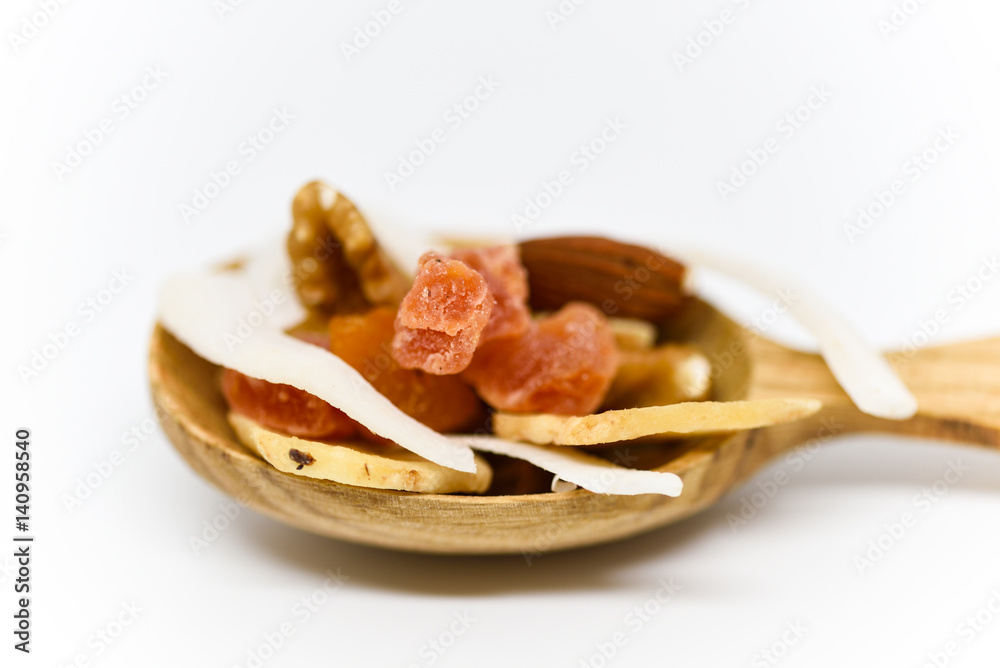 mixed dried fruit with nuts, coconut and banana served on decorative wooden spoon on white background macro close up mixed dried fruit with nuts, coconut and banana served on decorative wooden spoon on white background macro close up