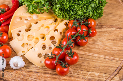 Cheese with fresh vegetables on a wooden background