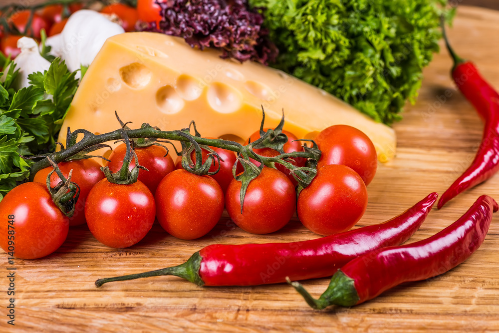 Cheese with fresh vegetables on a wooden background Cheese with fresh vegetables on a wooden background