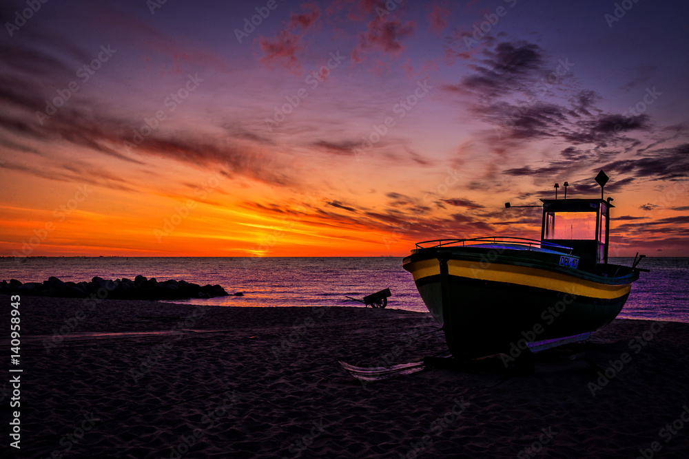 Obraz premium Wschód słońca z widokiem na morze i kuter