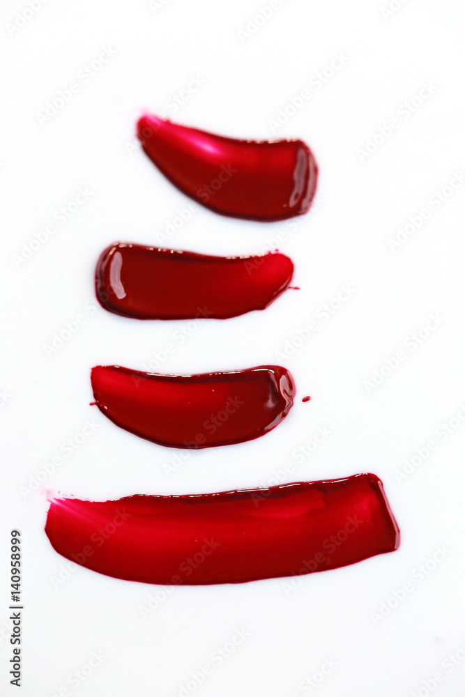 Fototapeta premium Texture of liquid red lipstick on white background. Four strokes