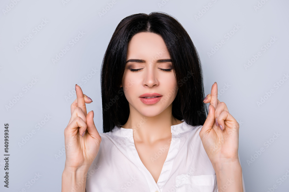 Portrait of young minded woman in white shirt with closed eyes and crossed hands waiting for success Portrait of young minded woman in white shirt with closed eyes and crossed hands waiting for success