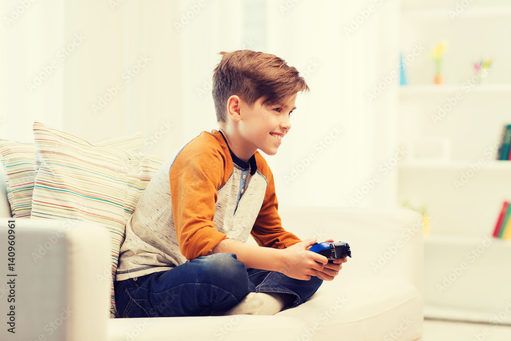 happy boy with joystick playing video game at home