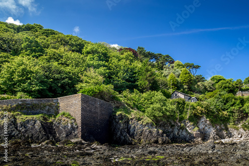 A small house at the foot of a hill overgrown with wood. The north coast of the Devon. England