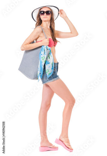 Pretty girl posing in bikini with bag, summer hat and sunglasses, isolated on white background © DenisNata