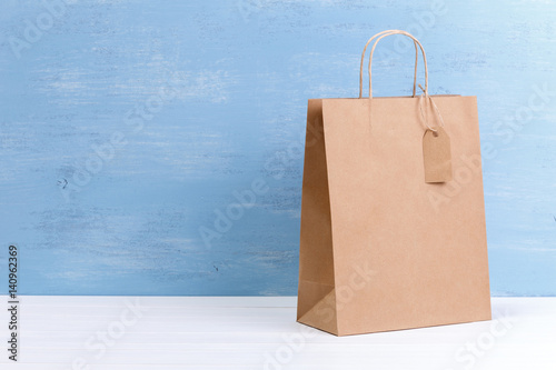 Mockup of blank shopping bag. Brown craft package. Concept for sales or discounts. Recycled paper. Blue wooden rustic board.