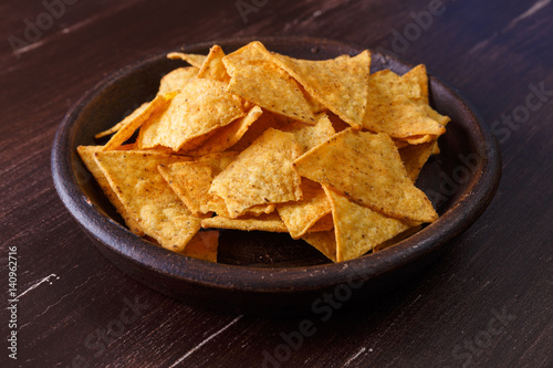 Nachos chips. Delicious salty tortilla snack on rustic plate. On wooden table background.