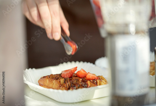 close up of cook hand adding strawberry to waffle