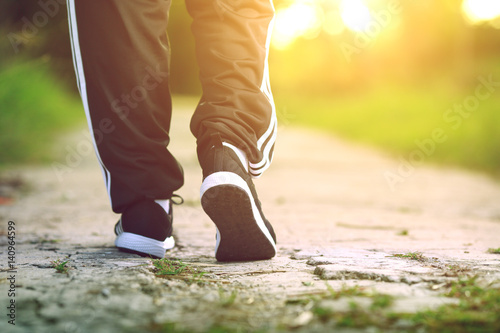Runner feet running on concrete road in park - fitness sunrise jog workout welness concept © bohbeh