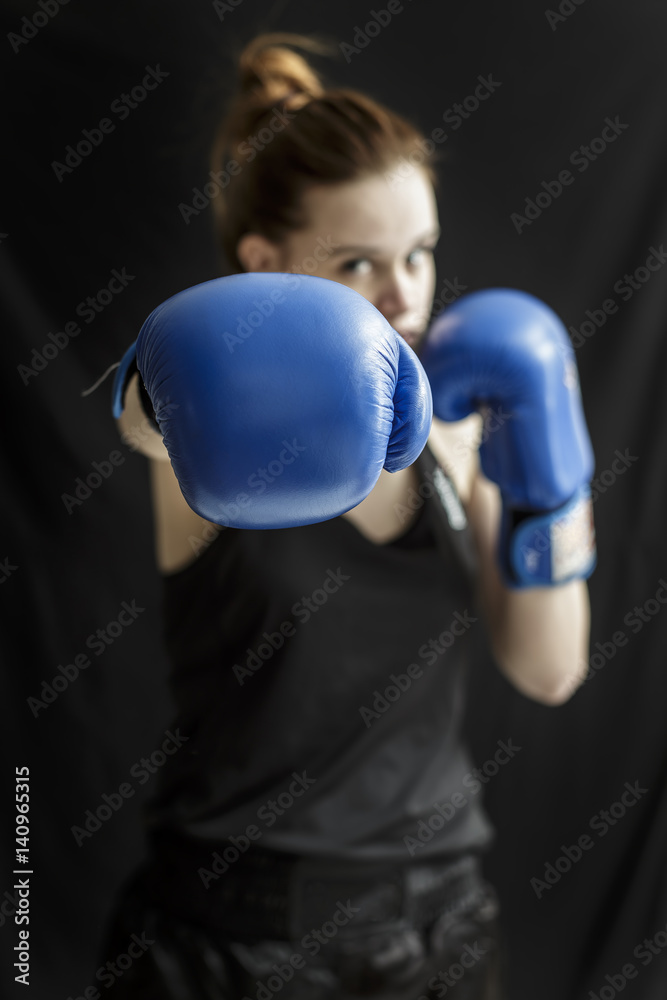 Attractive young girl fighter in blue boxing gloves makes a punch Attractive young girl fighter in blue boxing gloves makes a punch