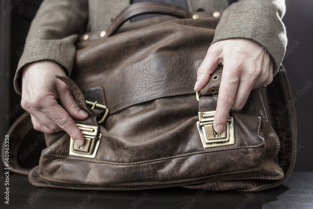 teacher in a jacket opens old leather briefcase standing on a table in the audience teacher in a jacket opens old leather briefcase standing on a table in the audience