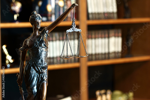 Goddess of justice statue in lawyer cabinet on bookshelf background