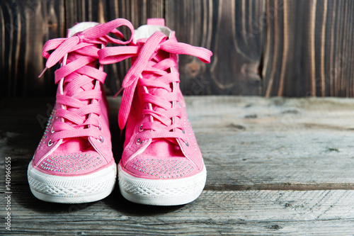 pair of bright pink sports sneakers on a wooden wall cracked