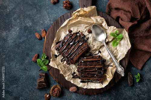 Chocolate brownie cake, dessert with nuts on dark background, directly above, flat lay photo
