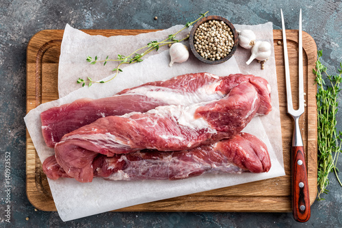 Cuadro en lienzo Fresh raw pork tenderloin on wooden cutting board on dark background