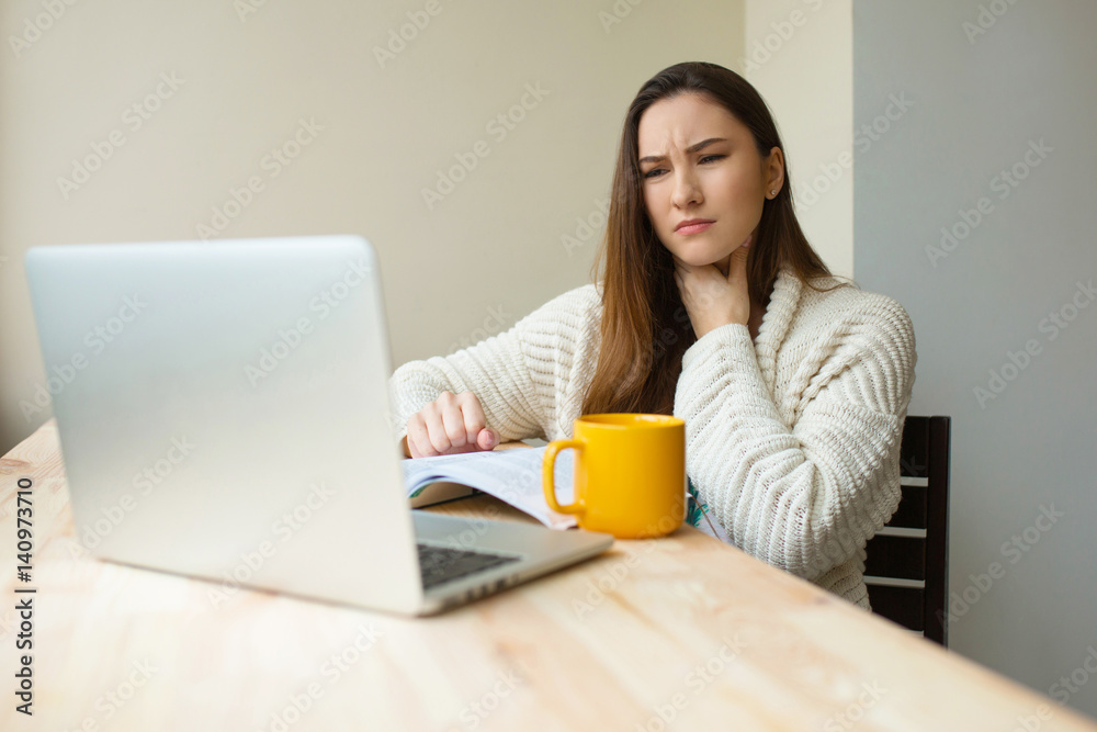 Sick girl at the laptop computer feeling hard pain in her throat working from home in cozy clothes. Ill woman studing Sick girl at the laptop computer feeling hard pain in her throat working from home in cozy clothes. Ill woman studing