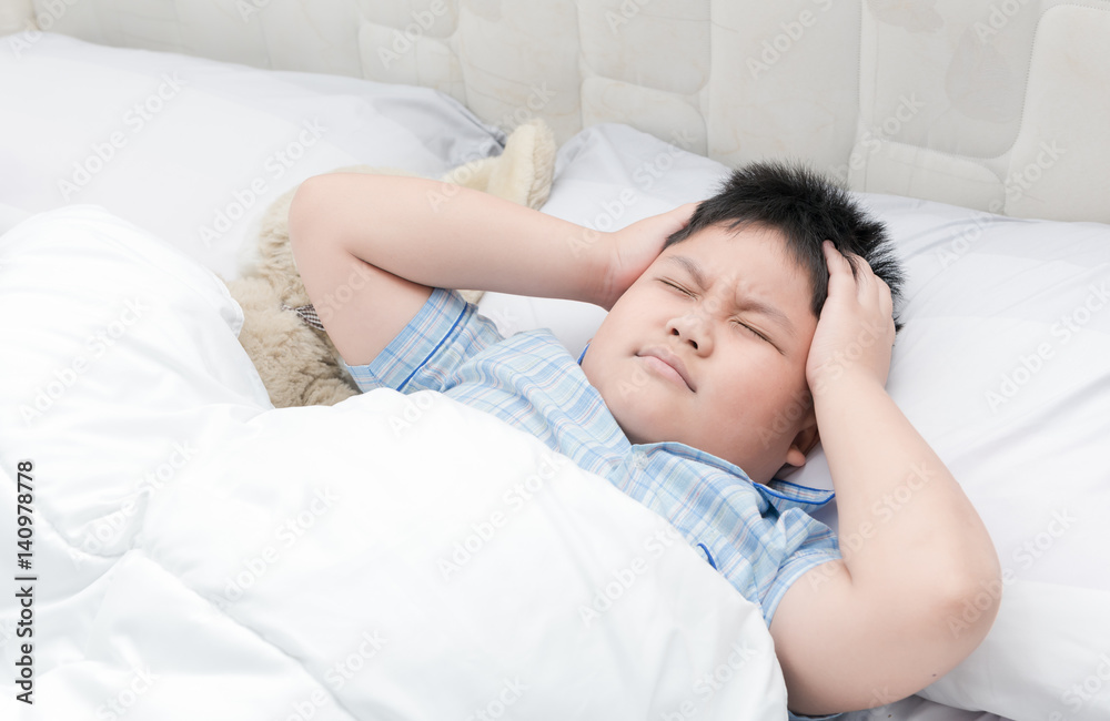 Child lying down suffering from a headache.