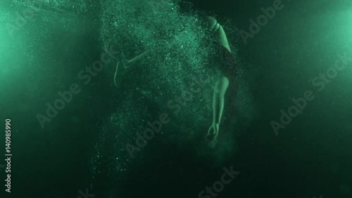 Woman in dress dives into pool, underwater