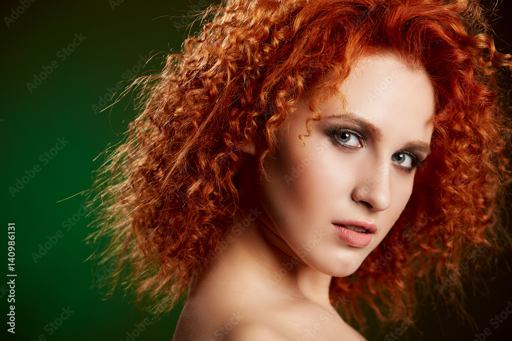 Girl with long and shiny wavy red hair . Beautiful model with curly hairstyle
