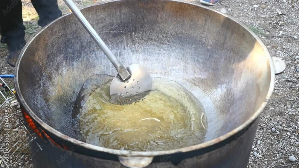 yellow oil in fry pan mixed with large spoon yellow oil in fry pan mixed with large spoon