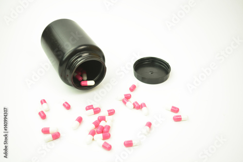 A black plastic bottle with pills