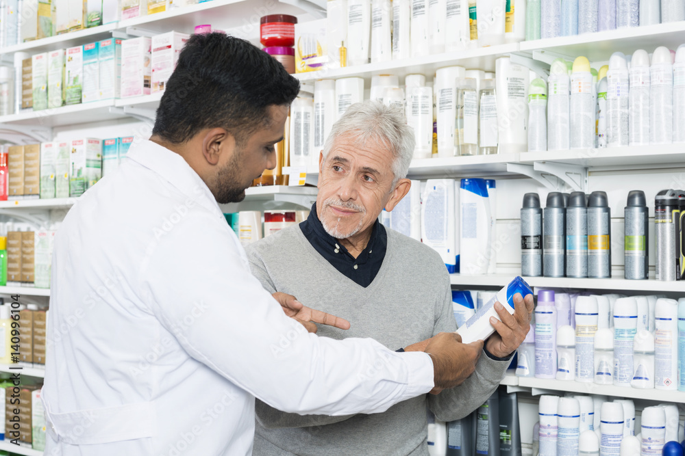 Pharmacist Assisting Senior Customer In Buying Product