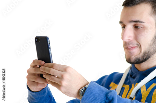 Teenager man concentrated using a smartphone with leather case isolated on white