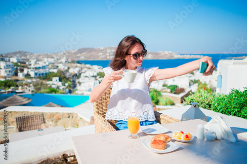 Young woman taking self portrait in outdoor cafe. Happy girl enjoy morning time in cafe with beautiful view
