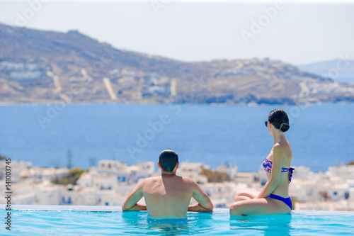 Happy young romantic family enjoy the view on the edge of swimming pool