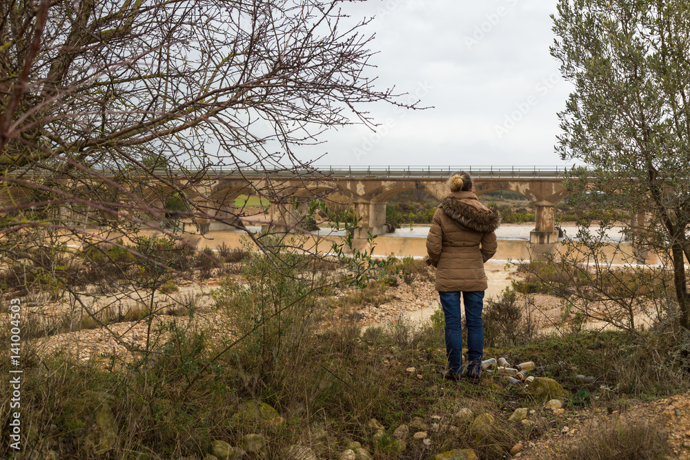 Kvinna tittar ut över flod och gammal bro Kvinna tittar ut över flod och gammal bro