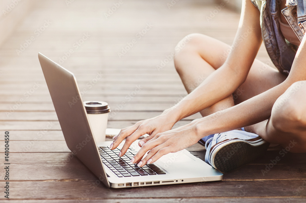Naklejka premium Young woman using laptop computer outdoors