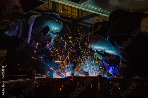Team workers are welding part in factory