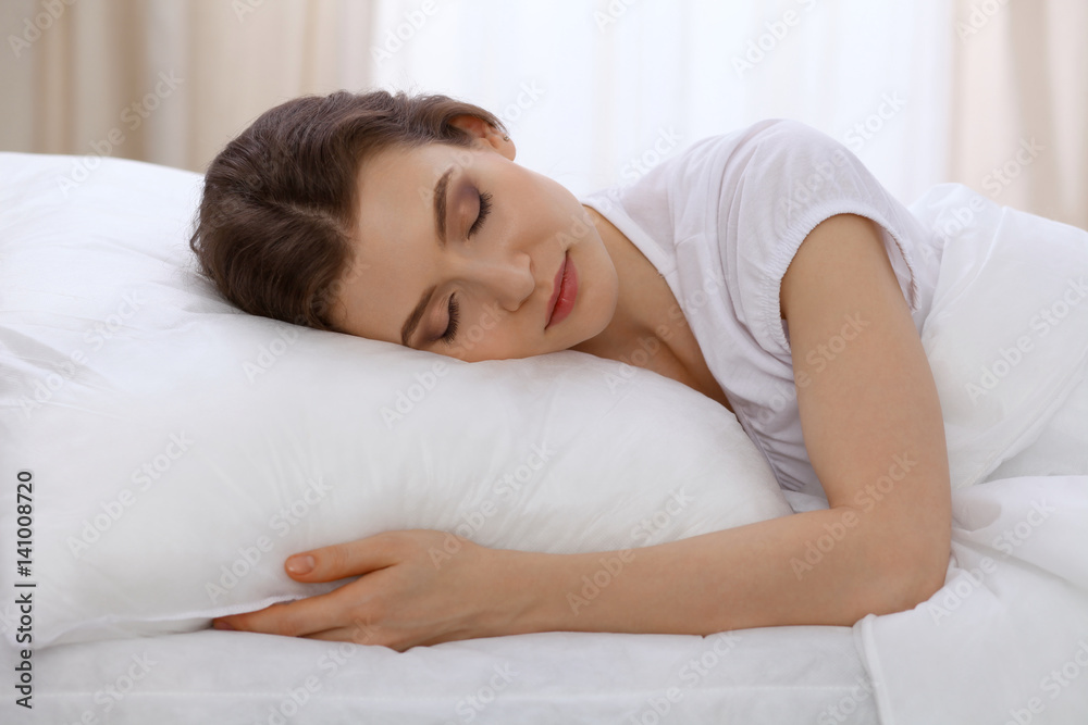 Beautiful young woman sleeping while lying in bed comfortably and blissfully. Early morning, you wake up for work or the day off concept Beautiful young woman sleeping while lying in bed comfortably and blissfully. Early morning, you wake up for work or the day off concept