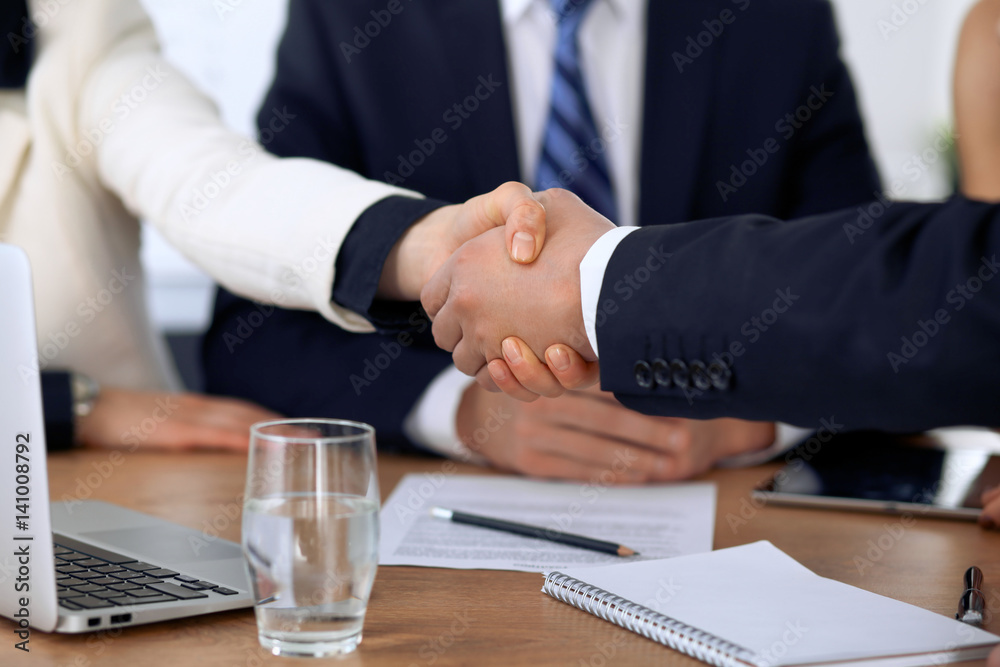 Close up of business people shaking hands at meeting or negotiation in the office. Partners are satisfied because signing contract