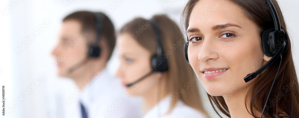 Call center operators. Focus at young beautiful business woman in headset. Call center operators. Focus at young beautiful business woman in headset.
