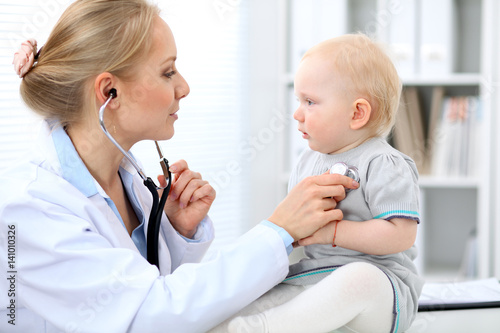 Pediatrician is taking care of baby in hospital. Little girl is being examine by doctor with stethoscope. Health care  medicine and help concept.