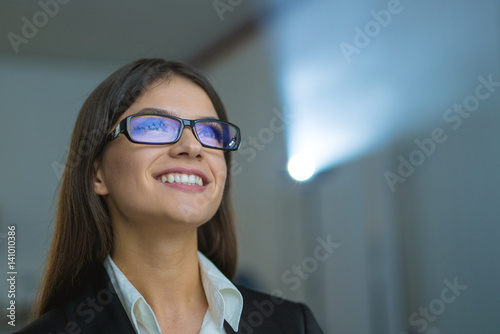 The happy woman with glasses on the background of projector