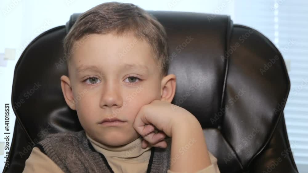 Serious boy in office on armchair, close-up Serious boy in office on armchair, close-up