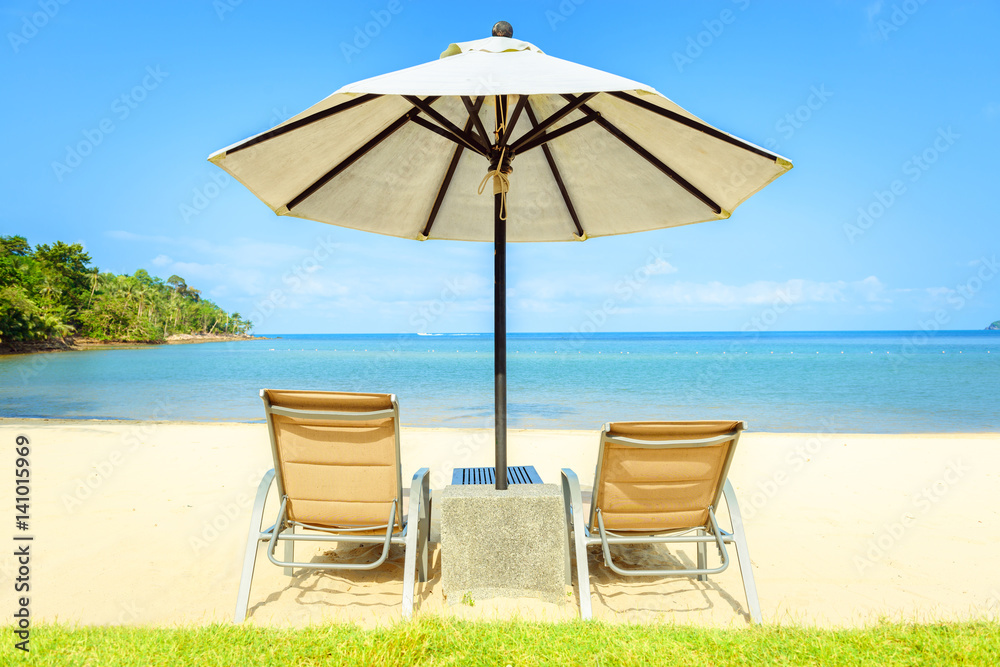 Beach chairs on the white sand beach with cloudy blue sky