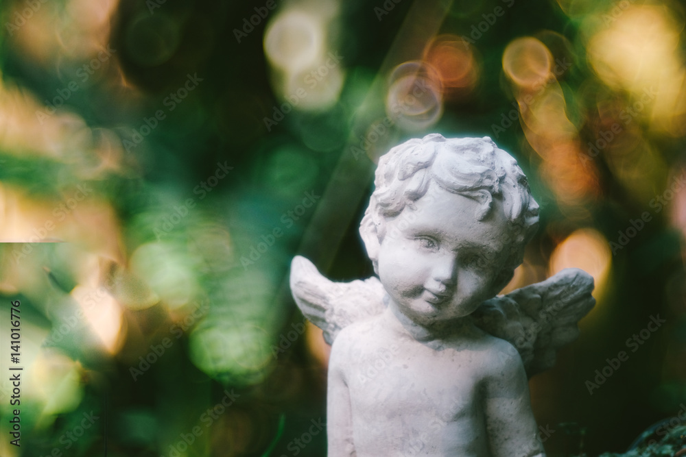 Cupid sculpture in garden the background is blurred bokeh from tree, background for Valentine's day. color toned.